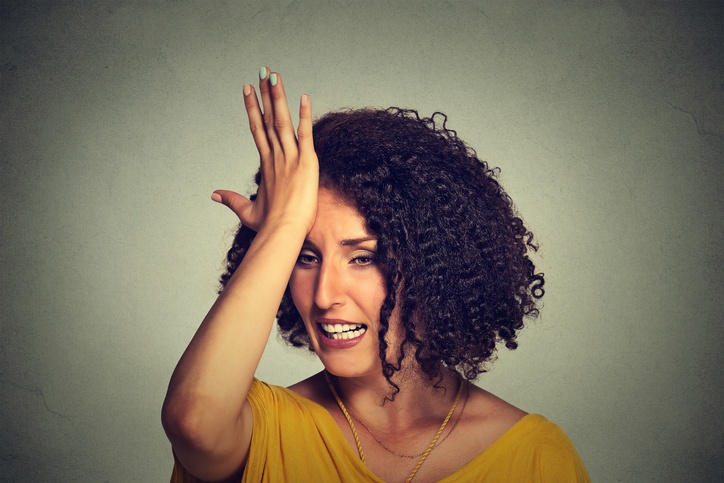 A woman, filled with buyer's remorse, smacks herself on the forehead in anguish.