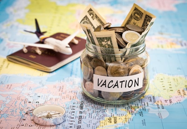 Vacation  money inside of a jar placed on top of map