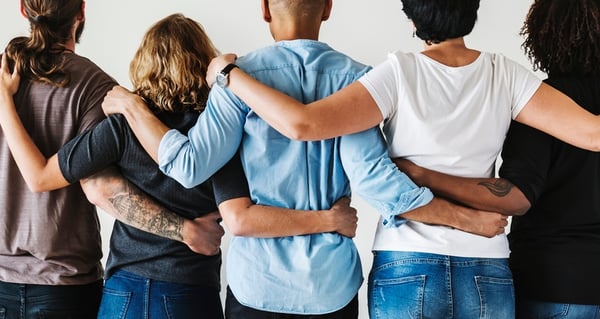 diverse group of people holding their arms around each other