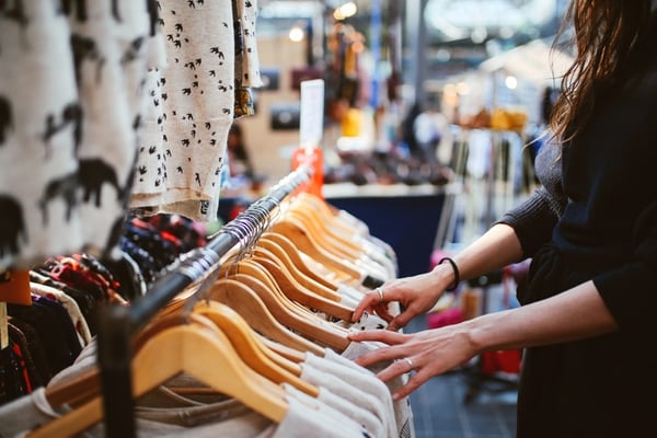 girl browsing rack of clothes at a small boutique