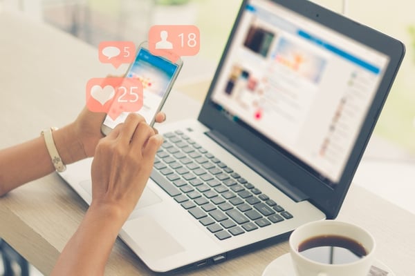 girl browsing social media on her laptop and phone while enjoying coffee