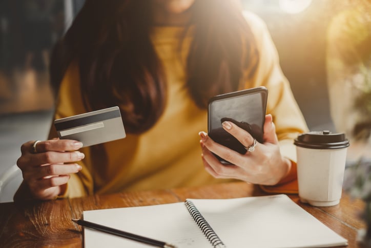 girl paying by phone with credit card in coffee shop