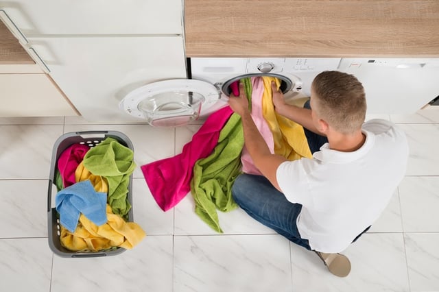 man filling washing machine with clothes