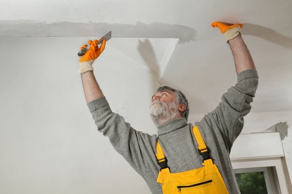 older man fixing popcorn ceiling