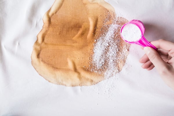 person using stain remover to get rid of stain on white shirt