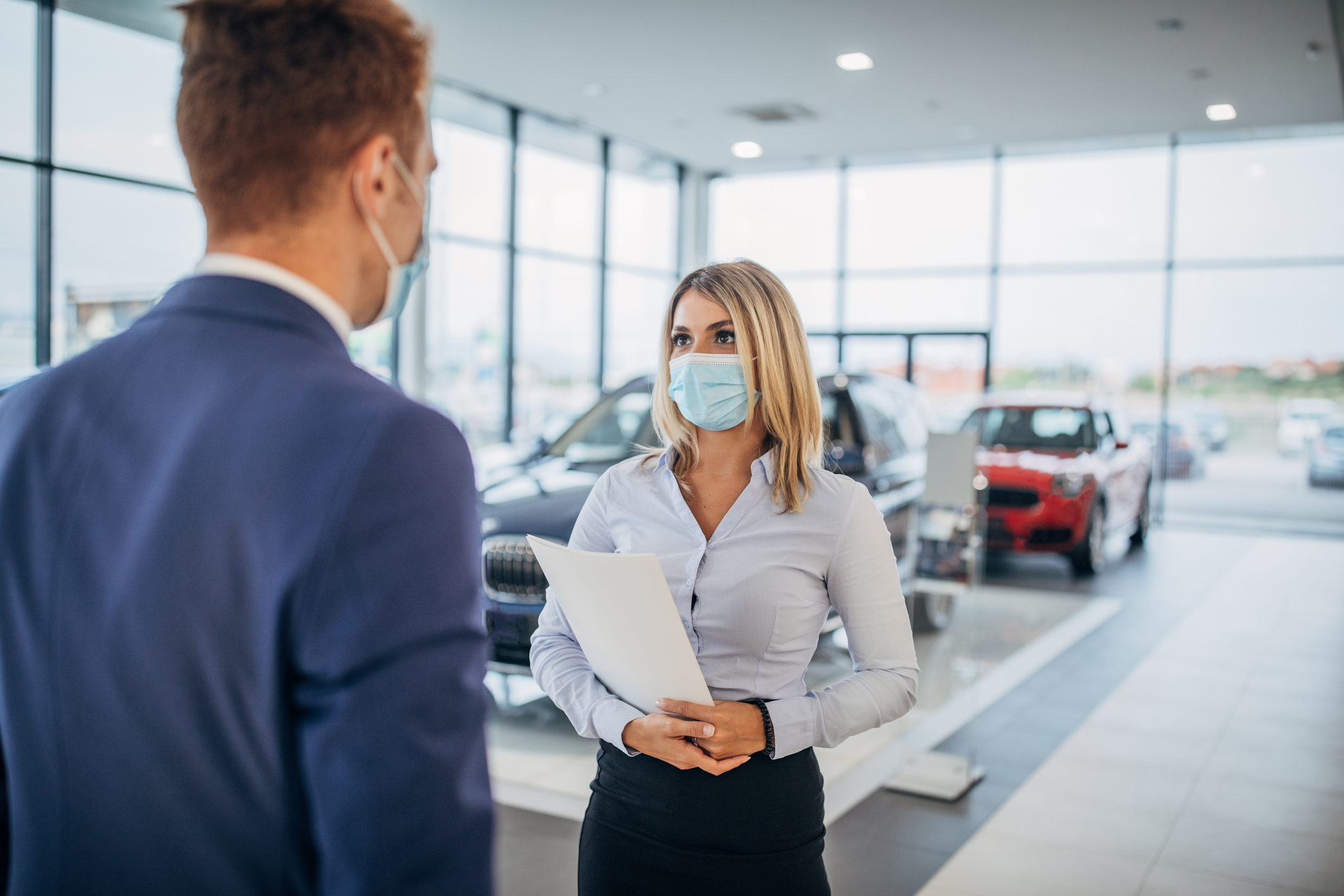 people wearing masks while shopping for a car 