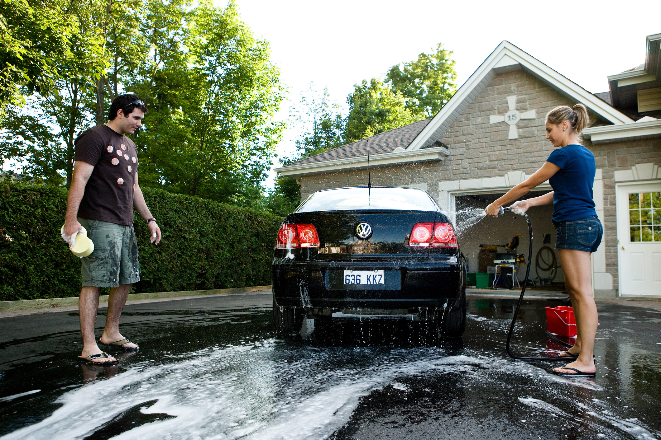 South Floridians washing car in Miami driveway 