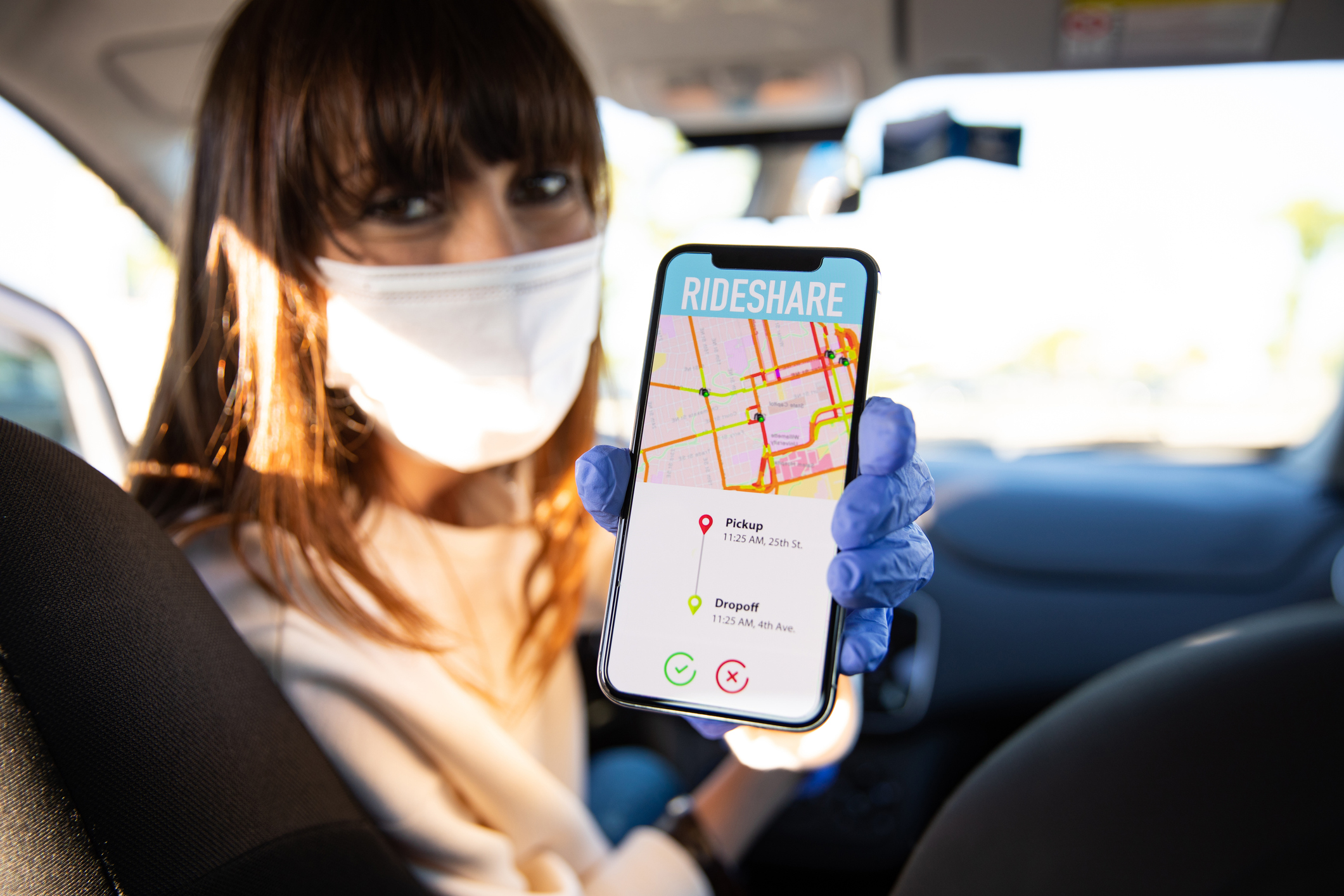 Rideshare driver holding phone with mask on 