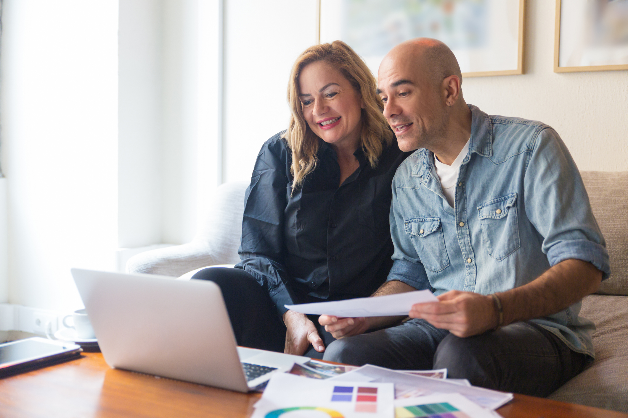 older couple sitting at couch looking over laptop home renovations