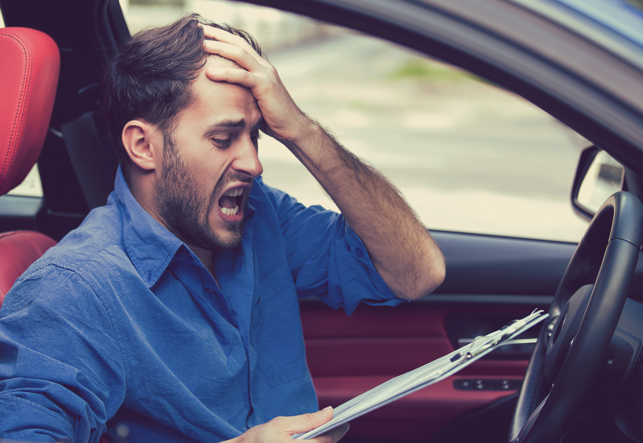 young man stressed reading fine print in car